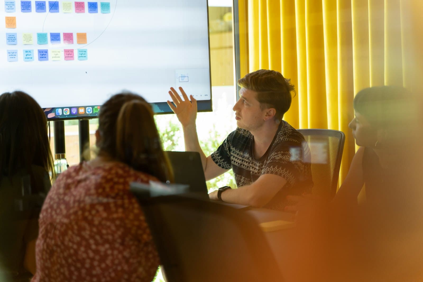 A student leading a group discussion in front of a screen of sticky notes