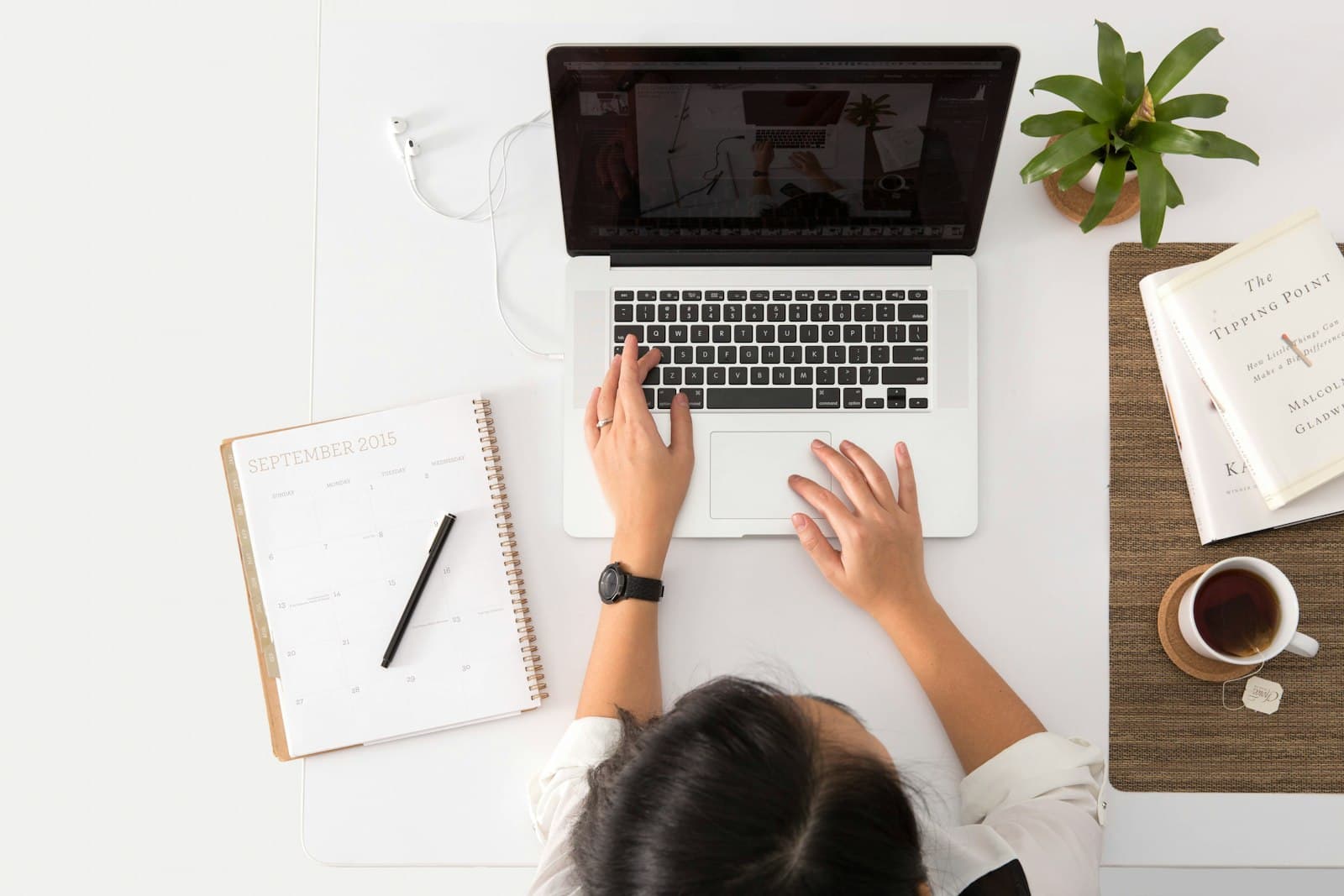 A student typing on a laptop at a tidy desk with a notebook and coffee