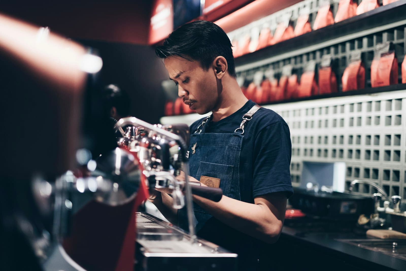 A young barista preparing coffee behind a café counter