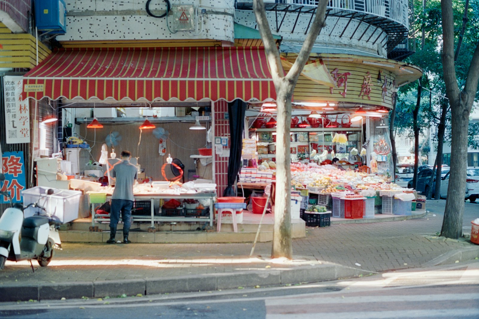 A small corner shop with a red awning and produce out front