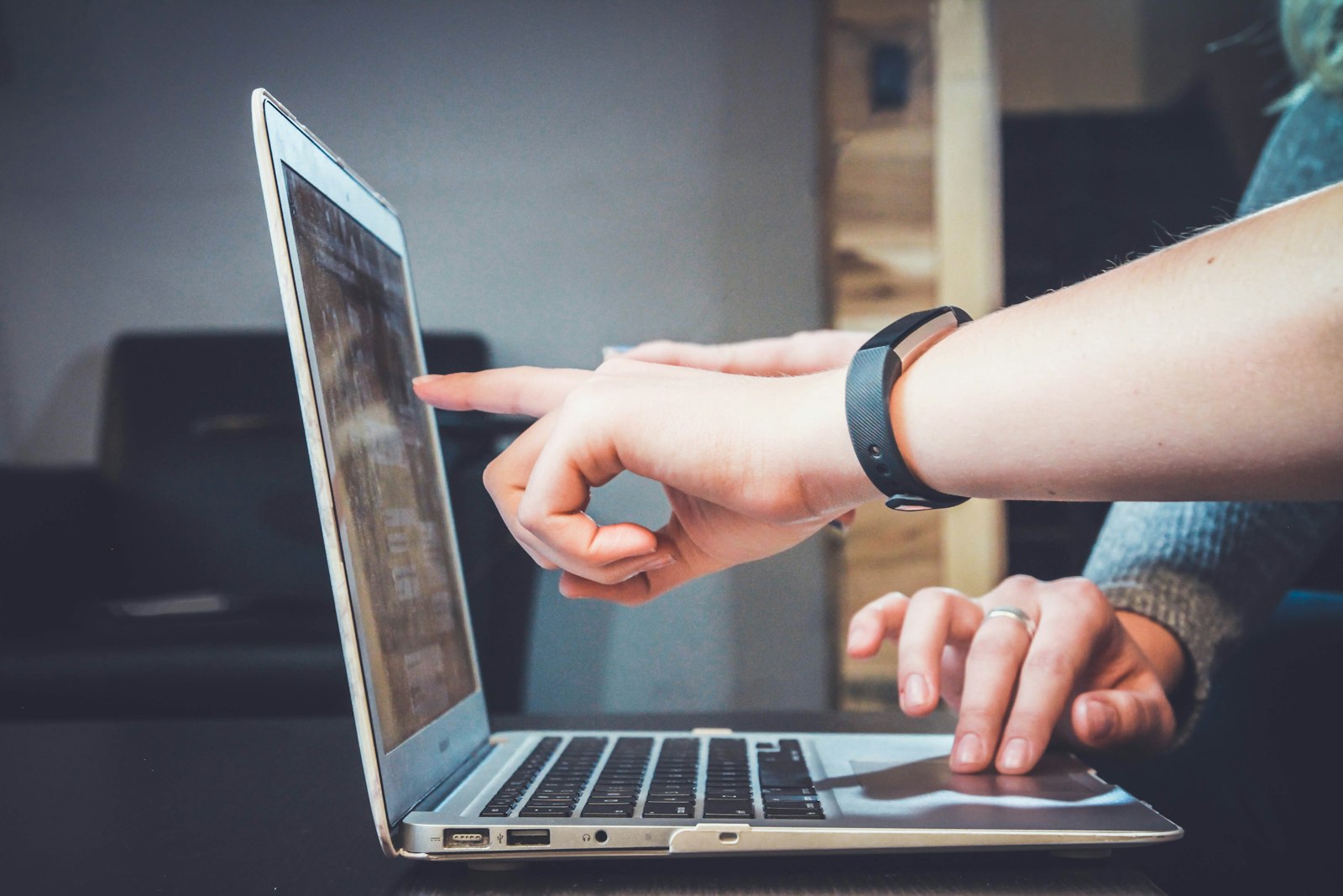 One person pointing at a laptop screen while another types