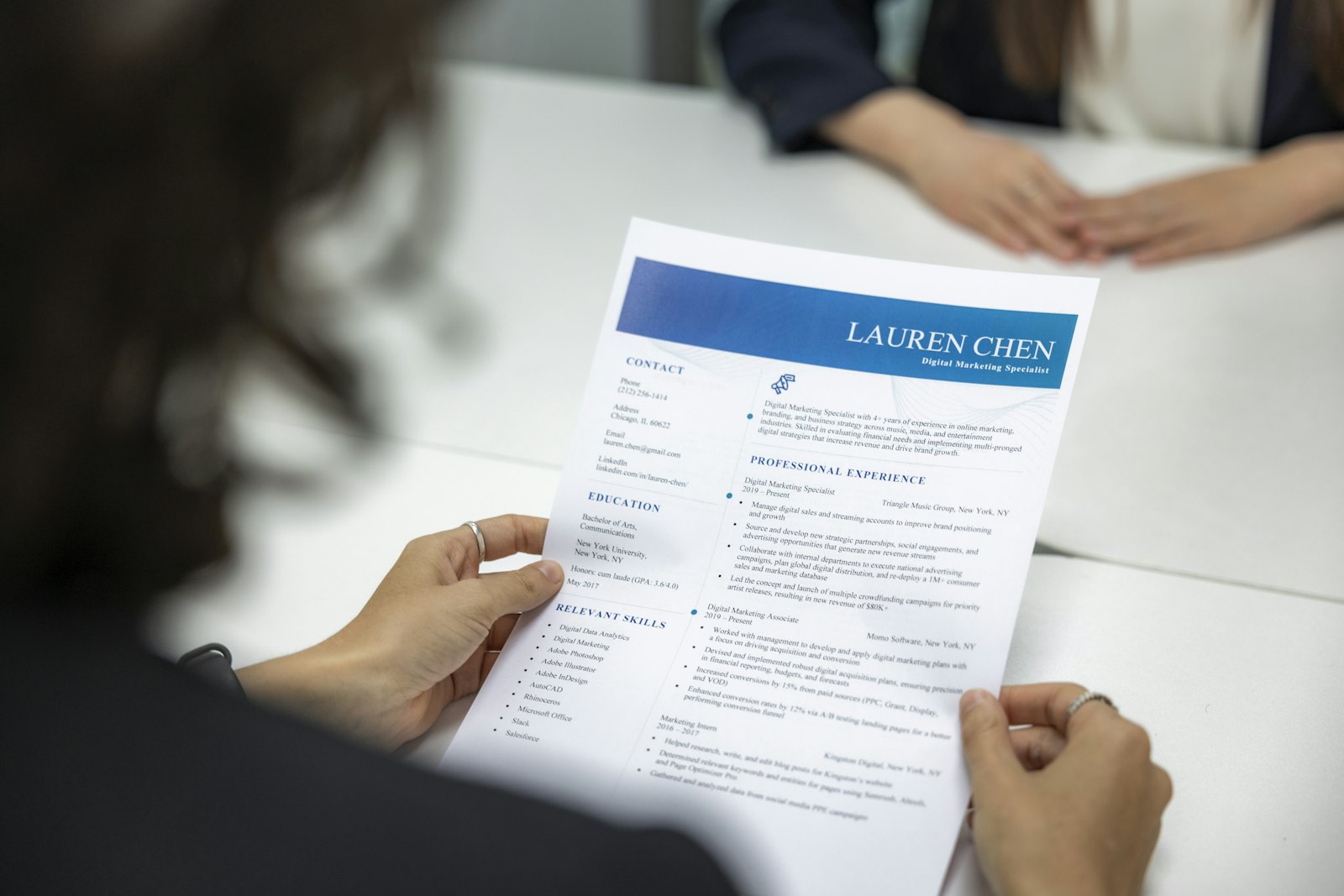 Someone holding a printed one-page résumé across a table during an interview