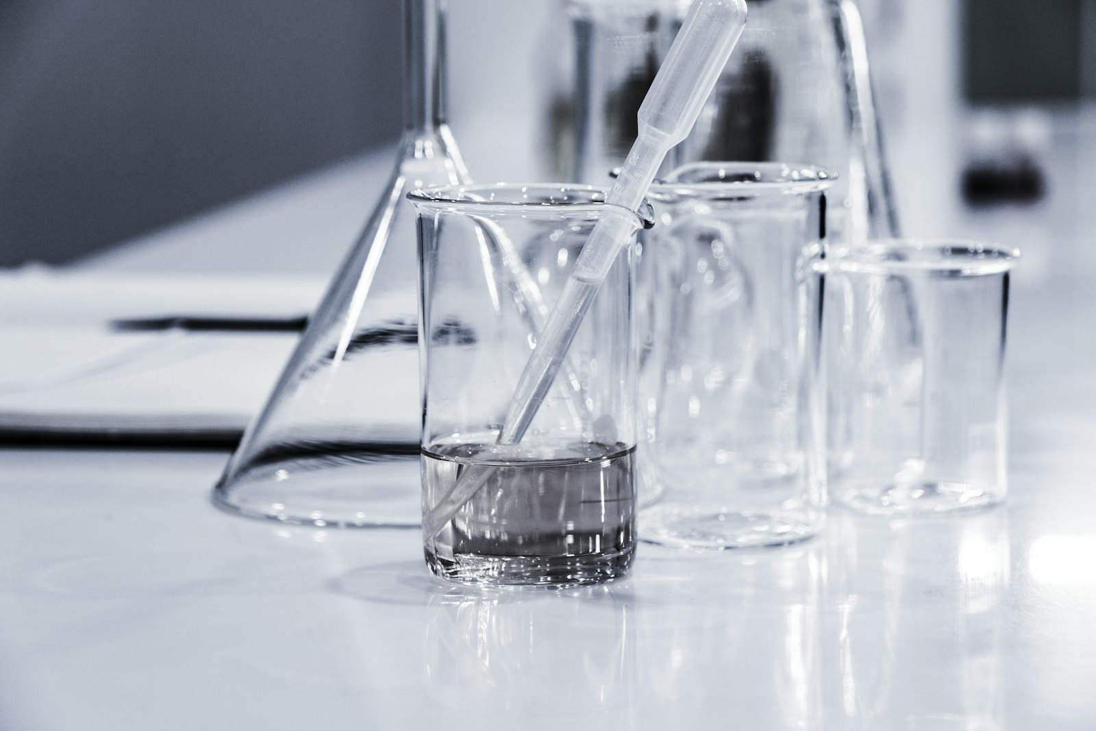 Glass beakers and a stirring rod on a white laboratory bench